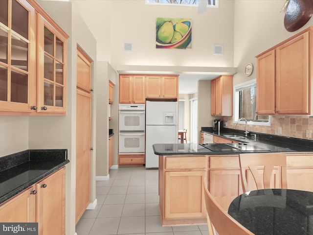 kitchen featuring light tile patterned flooring, light brown cabinetry, sink, kitchen peninsula, and white appliances