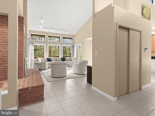 living room with light tile patterned flooring, high vaulted ceiling, and a brick fireplace