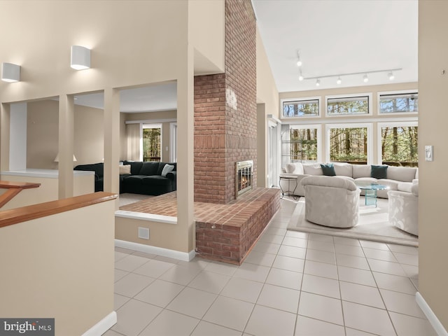 tiled living room with a brick fireplace, a towering ceiling, and track lighting