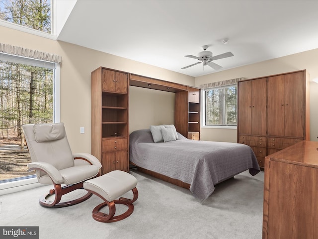 bedroom with ceiling fan, light colored carpet, and multiple windows