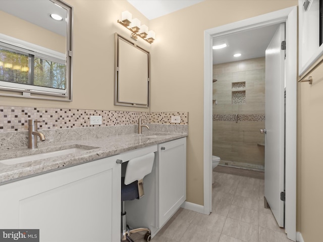 bathroom with vanity, a tile shower, backsplash, and toilet