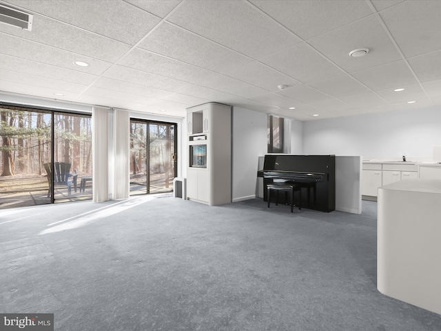 unfurnished living room with sink, dark carpet, and a paneled ceiling