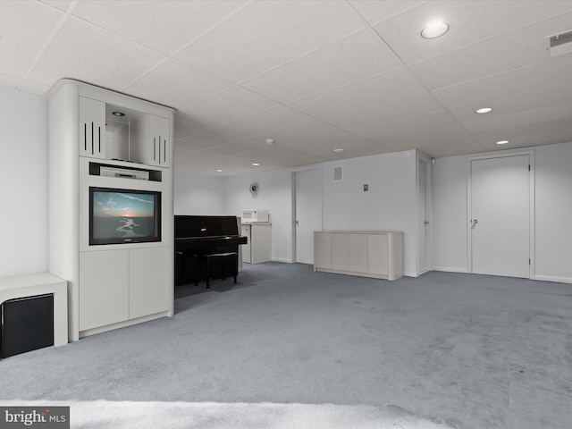 unfurnished living room with carpet floors and a drop ceiling