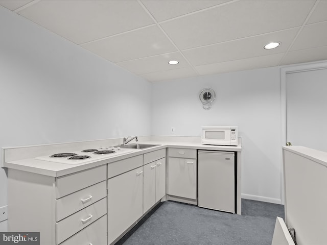 kitchen featuring white cabinetry, refrigerator, and a drop ceiling