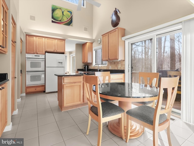 kitchen featuring white appliances, a wealth of natural light, decorative backsplash, and light brown cabinets