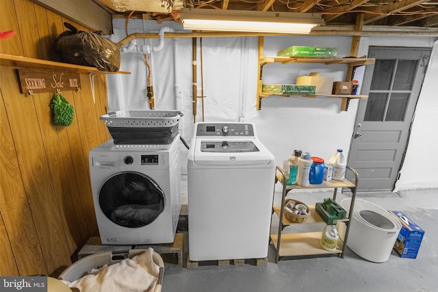 laundry area with washer and dryer and wooden walls