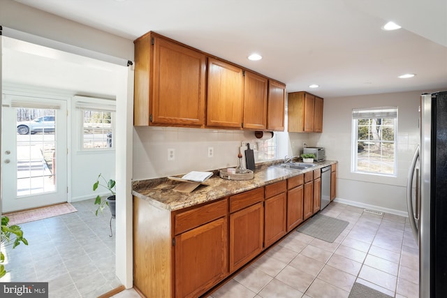 kitchen featuring recessed lighting, baseboards, appliances with stainless steel finishes, brown cabinets, and decorative backsplash