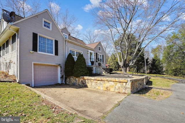 view of side of home featuring driveway and an attached garage