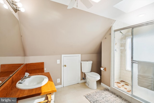 bathroom featuring toilet, lofted ceiling with skylight, a shower stall, and a sink