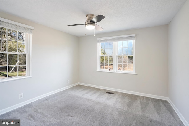 empty room with carpet, visible vents, a ceiling fan, a textured ceiling, and baseboards