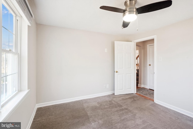 carpeted spare room featuring a ceiling fan and baseboards