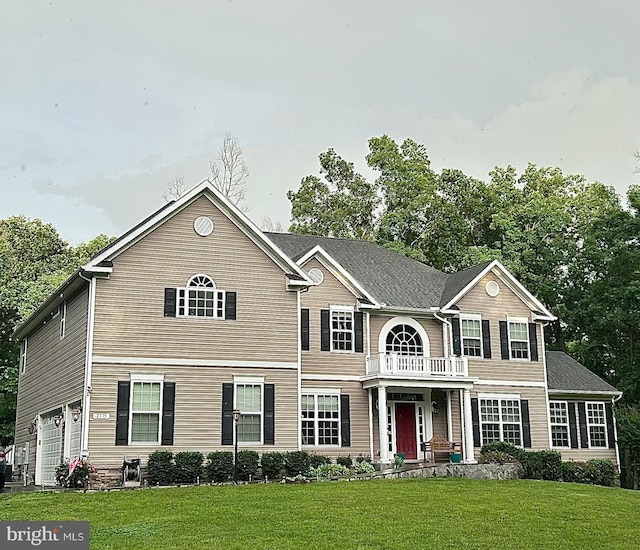 view of front facade with a balcony, a garage, and a front lawn