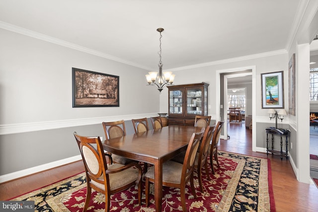 dining area with dark hardwood / wood-style floors, ornamental molding, and a notable chandelier