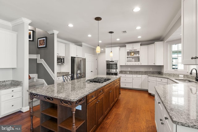 kitchen featuring a center island, sink, stainless steel appliances, decorative light fixtures, and white cabinets