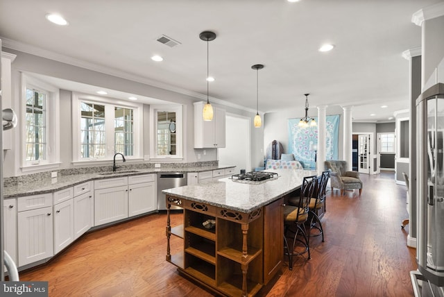 kitchen with white cabinets, appliances with stainless steel finishes, a kitchen bar, and sink