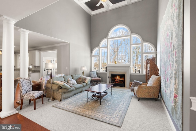 living room with crown molding, a towering ceiling, coffered ceiling, and ceiling fan