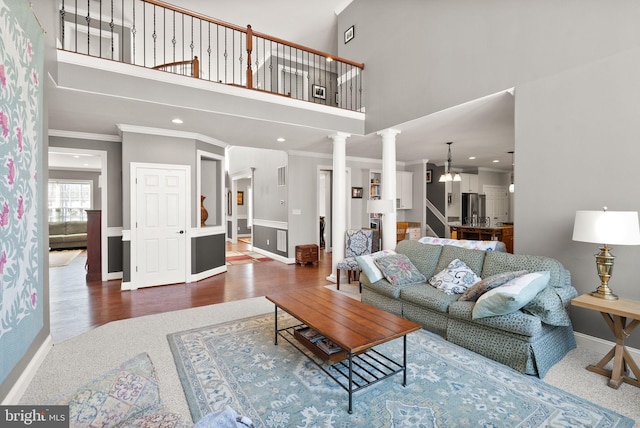 living room with hardwood / wood-style floors, a towering ceiling, decorative columns, and crown molding