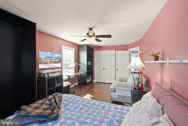 bedroom with ceiling fan, dark wood-type flooring, and two closets