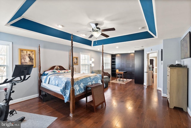 bedroom with a tray ceiling, ceiling fan, and dark hardwood / wood-style floors