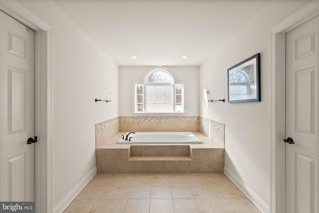 bathroom with tiled tub and tile patterned flooring