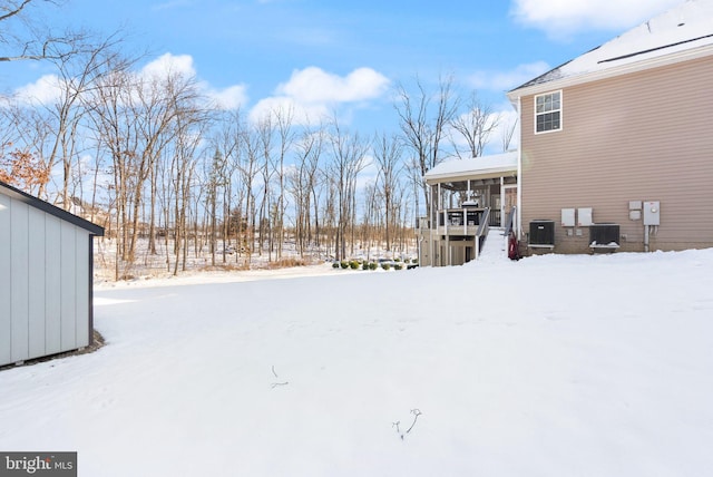 snowy yard featuring a sunroom and central air condition unit