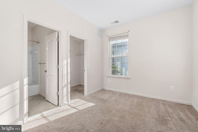 unfurnished bedroom with a walk in closet, light colored carpet, and a closet