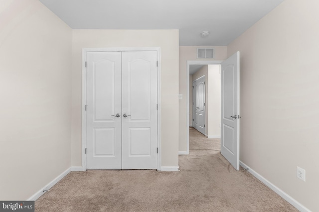 unfurnished bedroom featuring light carpet and a closet