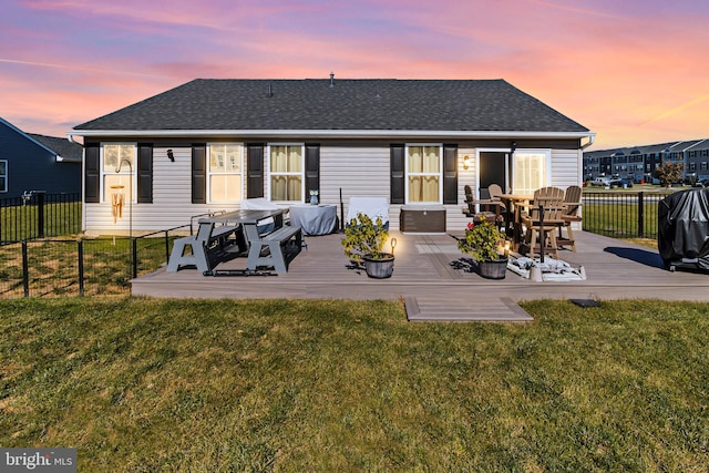 back house at dusk with a lawn and a wooden deck