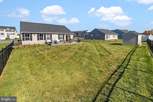 rear view of property with a yard, a patio, and a storage shed