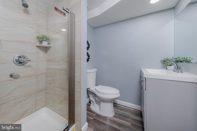 bathroom featuring tiled shower, hardwood / wood-style floors, vanity, and toilet