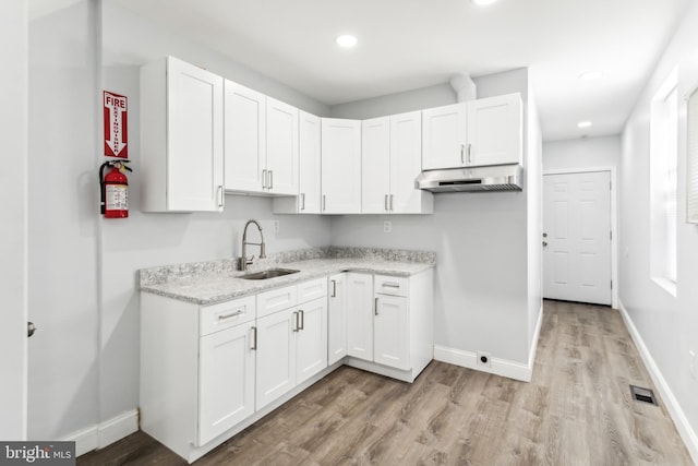 kitchen with white cabinets, light wood-type flooring, and sink