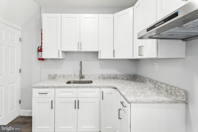 kitchen with white cabinets, light stone countertops, and sink