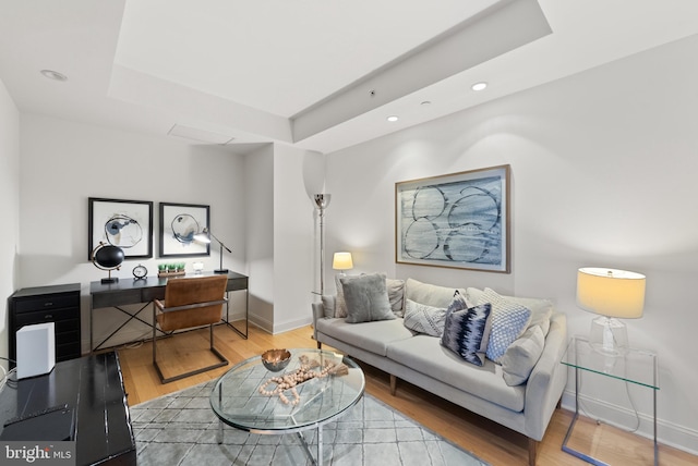 living room with hardwood / wood-style floors and a raised ceiling