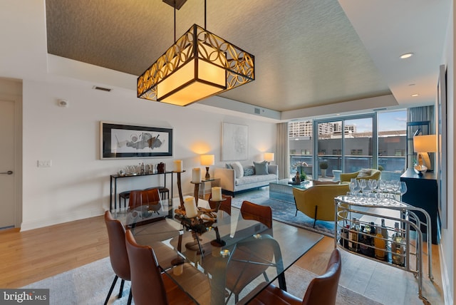 dining space featuring hardwood / wood-style flooring and a raised ceiling