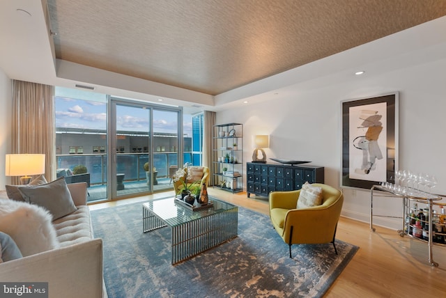 living room featuring hardwood / wood-style flooring, a raised ceiling, and expansive windows