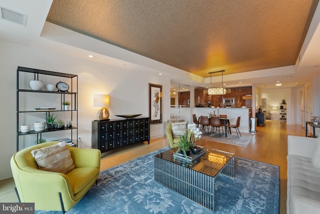 living room with hardwood / wood-style flooring and a raised ceiling