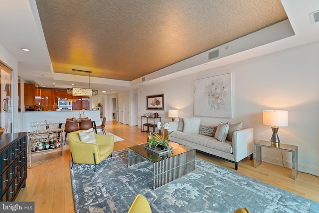 living room featuring light wood-type flooring and a tray ceiling