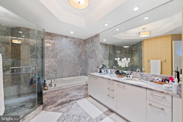 bathroom featuring a raised ceiling, vanity, independent shower and bath, and tile walls