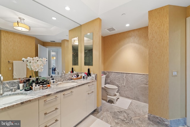 bathroom with vanity, toilet, and tile walls