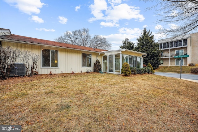 view of front of property featuring a front lawn, cooling unit, and a sunroom