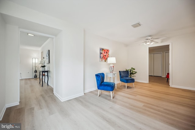 sitting room featuring light wood finished floors, baseboards, and a ceiling fan