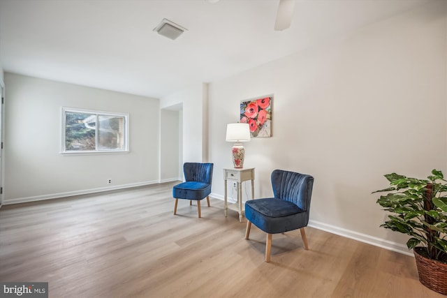 living area with light wood-type flooring, ceiling fan, and baseboards