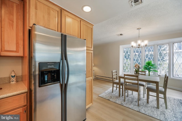 kitchen featuring visible vents, light countertops, stainless steel refrigerator with ice dispenser, light wood finished floors, and decorative light fixtures