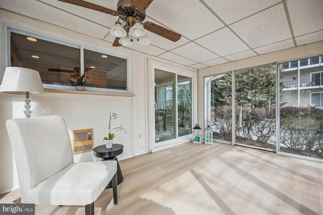 sunroom featuring a paneled ceiling, ceiling fan, and heating unit