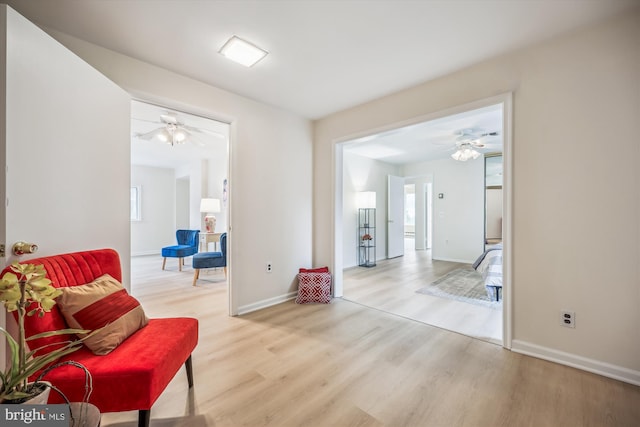 sitting room with ceiling fan, wood finished floors, and baseboards