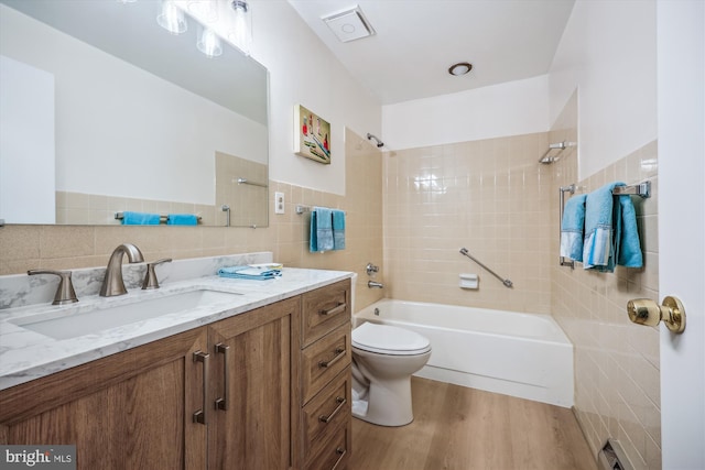 bathroom with bathing tub / shower combination, tile walls, toilet, vanity, and wood finished floors