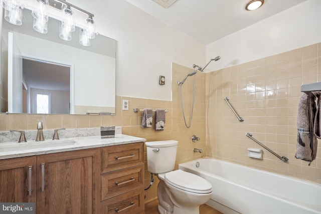 bathroom with toilet, vanity, tile walls, wainscoting, and washtub / shower combination