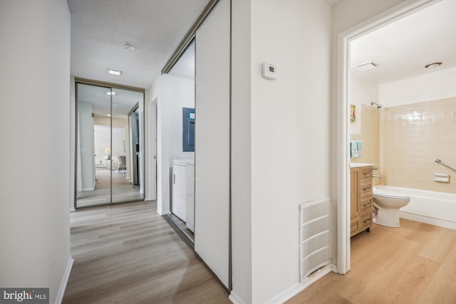 hall with washer / clothes dryer, a textured ceiling, and light wood finished floors