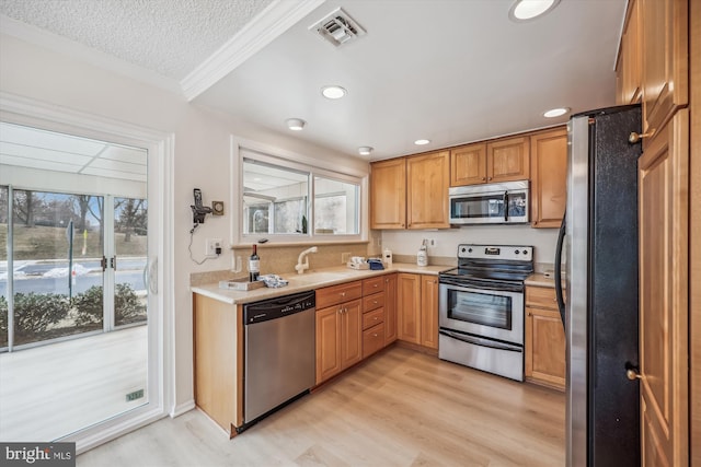 kitchen with visible vents, light wood-style flooring, appliances with stainless steel finishes, light countertops, and a sink