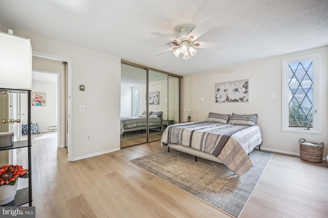 bedroom featuring light wood-type flooring, a closet, a textured ceiling, and baseboards